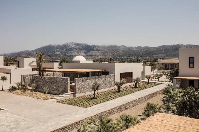 Low white buildings around a planted courtyard under bright light